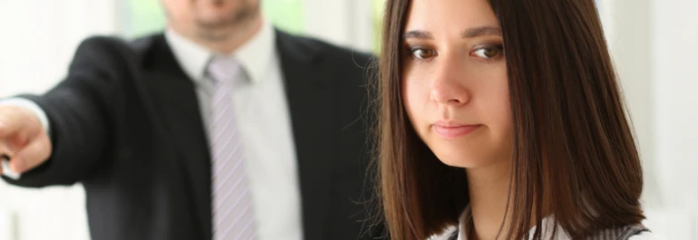  Un hombre señala hacia una mujer que mira a la cámara. 