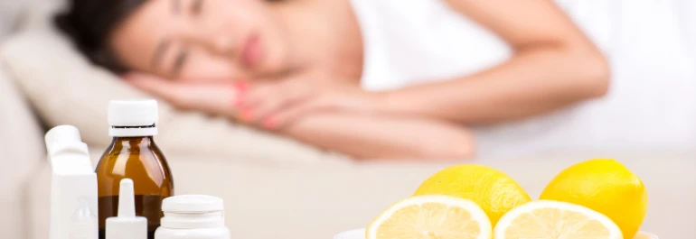  Una mujer duerme en segundo plano mientras en primer plano se ven medicinas y limones. 