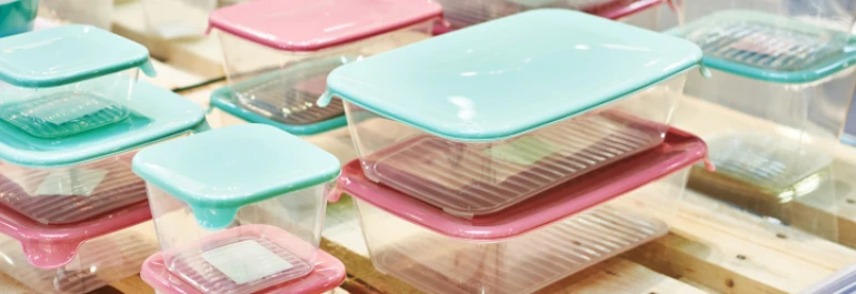  Contenedores de plástico con tapas de colores pastel organizados sobre una superficie de madera. 