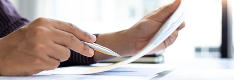  mano sujetando un papel con gráficos y con la otra señalando con el boli 