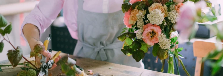  Una persona arregla un ramo de flores sobre una mesa. 