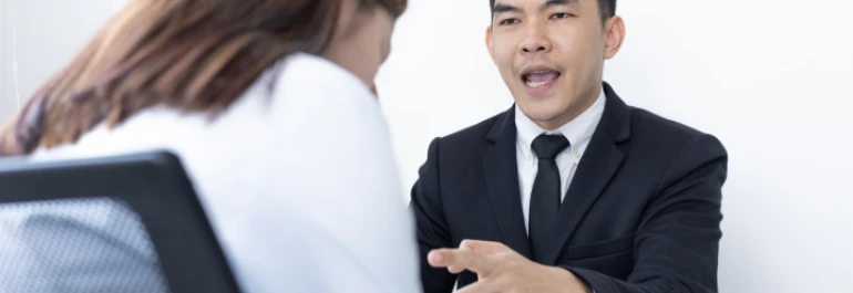  Una persona en traje negro hablando con otra persona de cabello largo. 