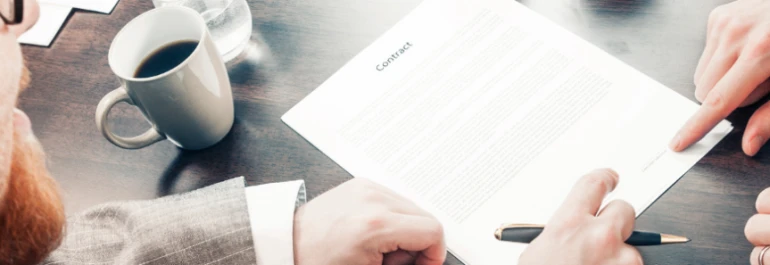  Dos personas revisan un documento sobre una mesa con una taza de café al lado. 