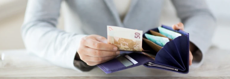  Una persona sostiene una billetera abierta con billetes visibles. 