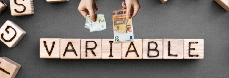  Manos sosteniendo billetes sobre bloques que forman la palabra VARIABLE. 