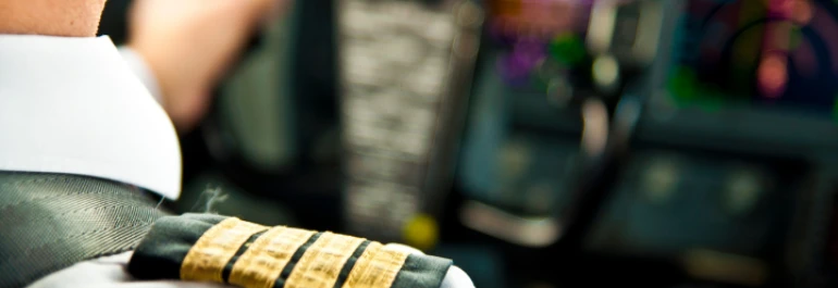  Un piloto con uniforme está en la cabina de mando de un avión. 