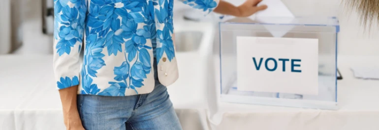  Una persona está depositando un voto en una urna transparente. 