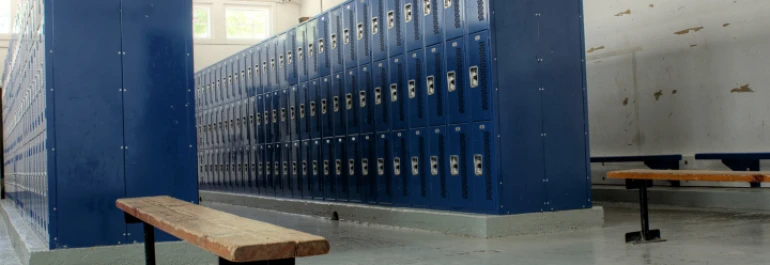  Un vestuario con casilleros azules y bancos de madera. 