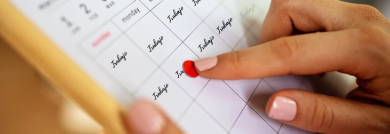  Una persona marca un día en un calendario que tiene la palabra Trabajo escrita repetidamente. 