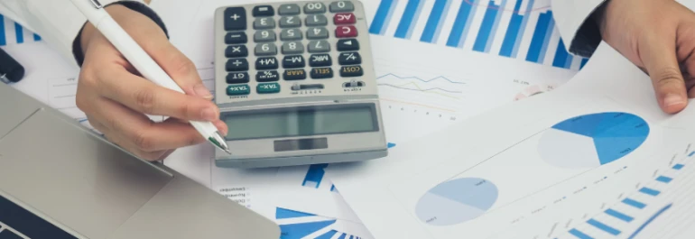  Una persona revisa gráficos financieros utilizando una calculadora y una computadora portátil. 