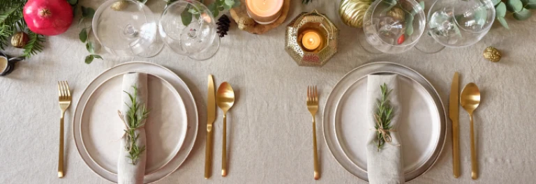  mesa montada con cubiertos dorados, velas, ramas y adornos navideños 