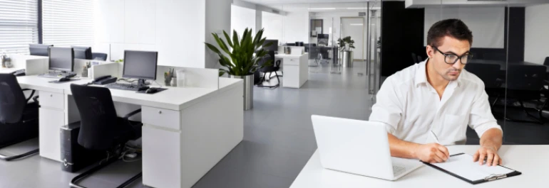  Un hombre escribe en un documento en un moderno y luminoso entorno de oficina. 