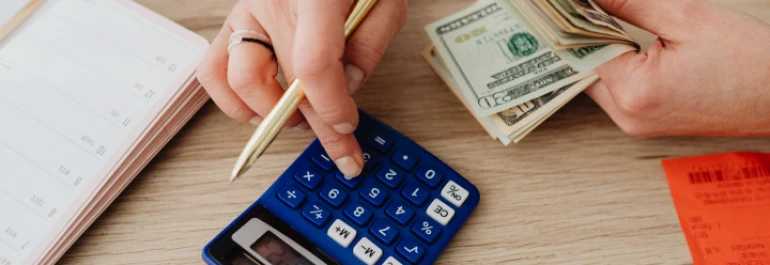  Una persona cuenta dinero mientras usa una calculadora. 