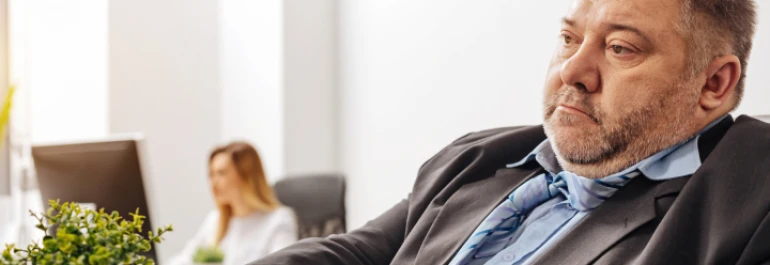  Un hombre con gesto pensativo está sentado en una oficina. 