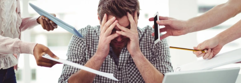  Un hombre parece abrumado mientras varias manos le entregan papeles, un teléfono y una pluma. 
