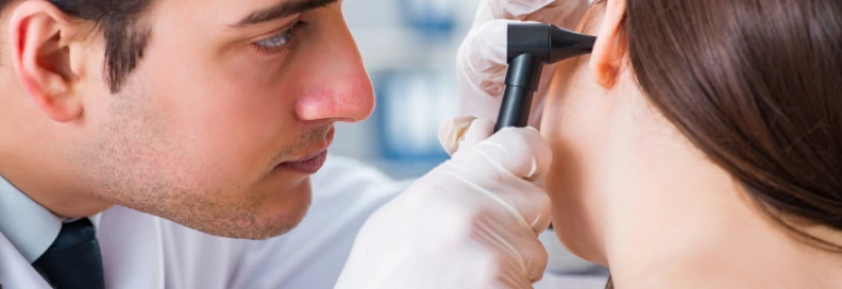  Un médico está examinando el oído de una paciente con un otoscopio. 