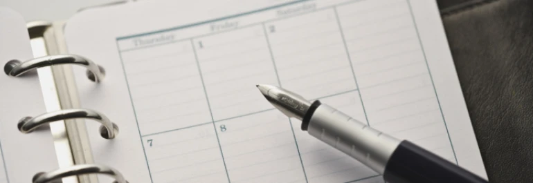  calendario dentro de una agenda con una pluma encima 