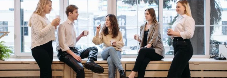  Cinco personas están conversando y tomando café en una oficina. 