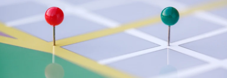  Dos chinchetas de colores sobre un mapa de cuadrícula. 