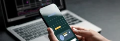  Persona sujetando un smartphone con un calendario abierto y un ordenador portátil en segundo plano 