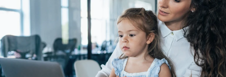  Una mujer y una niña están frente a una computadora en un entorno de oficina. 