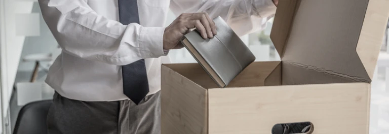  Hombre en camisa y corbata empacando agenda en caja de cartón 