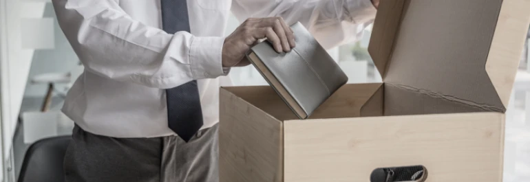  Hombre en camisa y corbata empacando agenda en caja de cartón 
