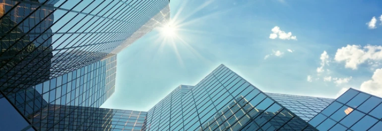  Edificios modernos de cristal reflejando la luz del sol bajo un cielo despejado. 