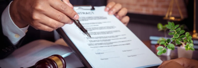  Una persona sostiene y señala un contrato con un bolígrafo. 