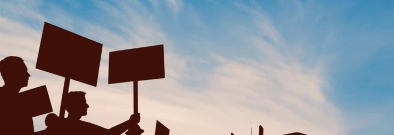  Siluetas de personas sosteniendo carteles sobre un fondo de cielo azul. 
