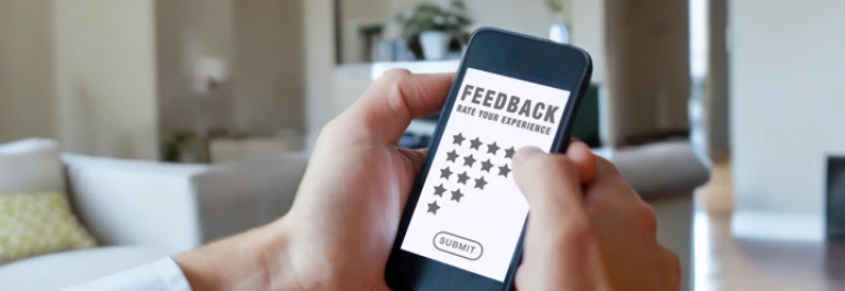  Una persona sosteniendo un teléfono que muestra una pantalla de retroalimentación con estrellas para calificar una experiencia. 