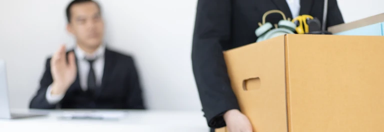  Hombre de traje despidiéndose de otro que está llevándose sus cosas en una caja 