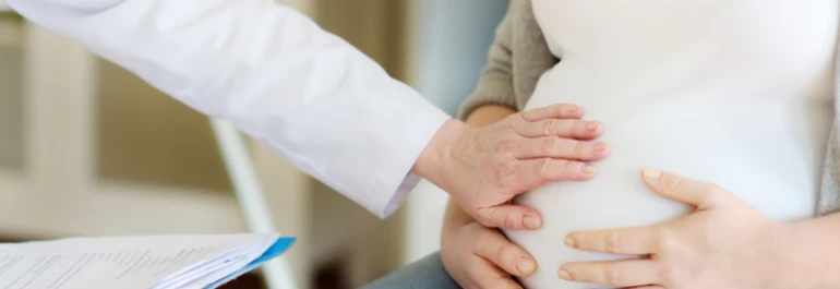  Un médico examina el abdomen de una mujer embarazada. 