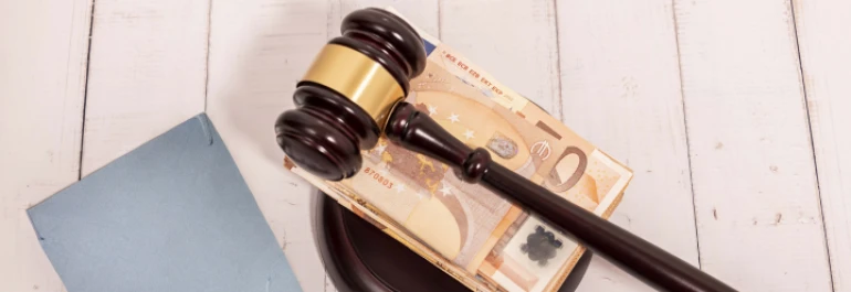  Un mazo judicial descansa sobre billetes de euro y un documento. 