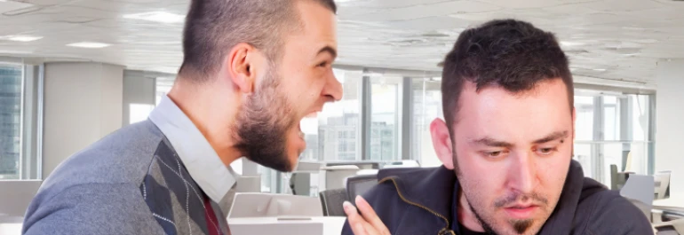  Una persona grita a otra que parece incómoda en una oficina. 