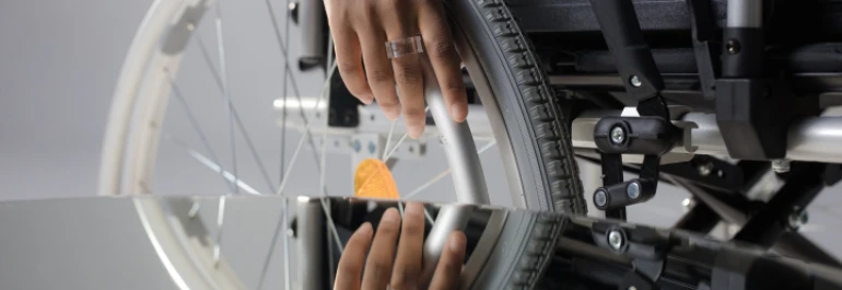  mano sujetando rueda de silla de ruedas frente a reflejo 