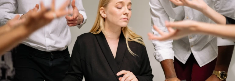  Mujer rubia con americana negra sentada entre hombres gesticulando con las manos 