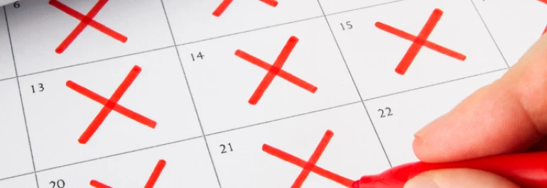  Una mano marca cruces rojas en los días de un calendario. 