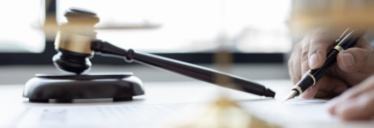  Persona escribiendo con pluma junto a mazo de juez 