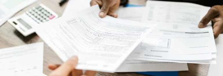  Personas revisando documentos en una mesa de trabajo. 