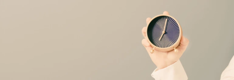  Una mano sostiene un reloj de mesa con diseño minimalista. 