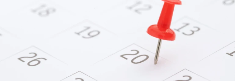  Una chincheta roja marca el día 20 en un calendario. 