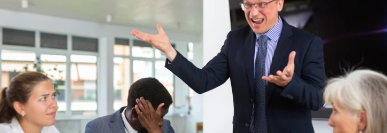  Hombre gritando y gesticulando en una reunión con compañeros de trabajo 