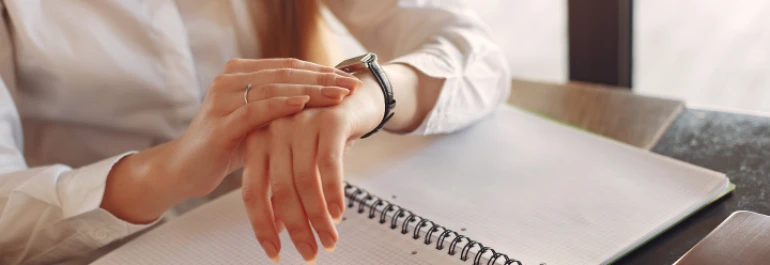  Mujer levantando las manos sobre un cuaderno para poder ver su reloj 