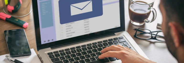  Una persona revisa sus correos electrónicos en una computadora portátil con una taza de café al lado. 