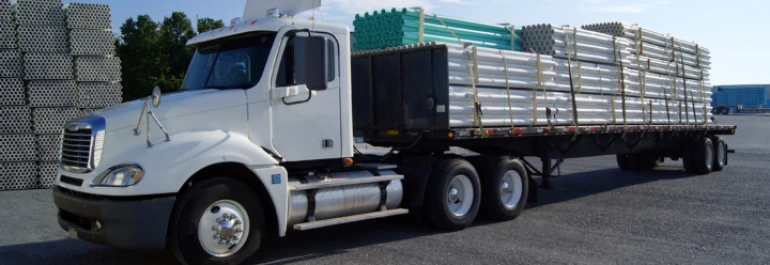  Un camión de carga transporta tubos metálicos apilados en su remolque. 