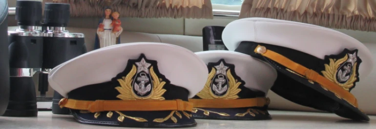  Tres sombreros de marinero junto a binoculares y una virgen 