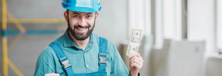  Un trabajador con casco azul sostiene un billete y muestra una expresión de éxito. 