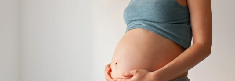  Una mujer embarazada sostiene su vientre. 