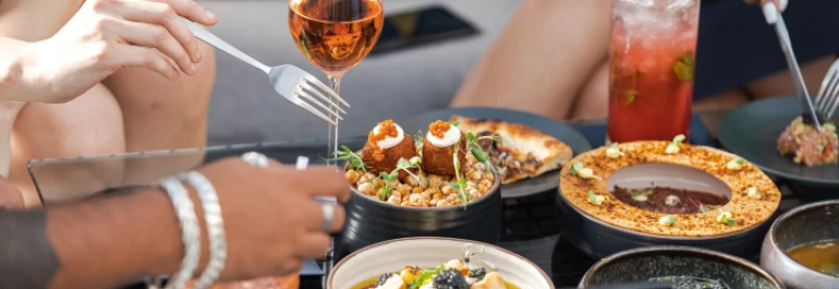  Personas disfrutando de una variedad de platos y bebidas gourmet en una mesa. 
